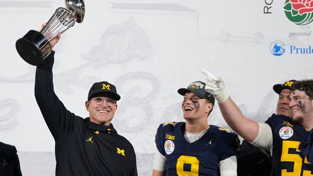 Michigan head coach Jim Harbaugh holds the winner's trophy next to quarterback J.J. McCarthy (9) after a win over Alabama in the Rose Bowl CFP NCAA semifinal college football game Monday, Jan. 1, 2024, in Pasadena, Calif. (AP Photo/Mark J. Terrill)