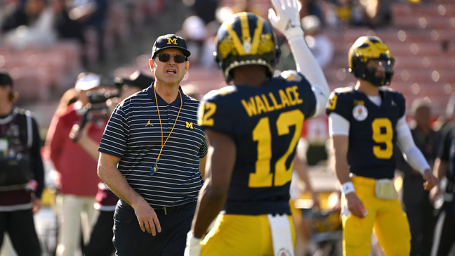 Michigan head coach Jim Harbaugh, left, and defensive back Josh Wallace (12) talk on the field before the Rose Bowl CFP NCAA semifinal college football game against Alabma Monday, Jan. 1, 2024, in Pasadena, Calif. (AP Photo/Kyusung Gong)